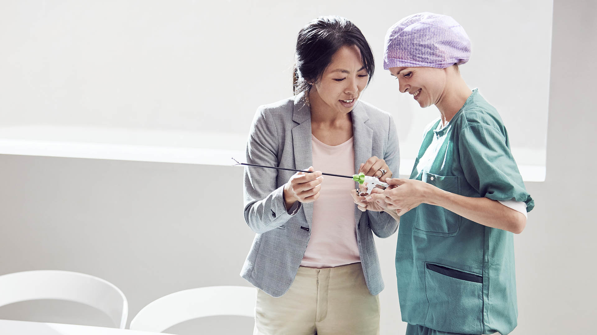vrouwelijke leverancier die een chirurgisch instrument aan een vrouwelijke zorgprofessional demonstreert