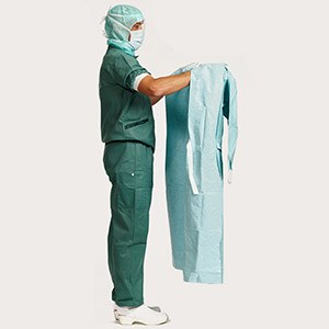 Professionele zorgverlener toont de tweede stap van het aantrekken van een operatiejas