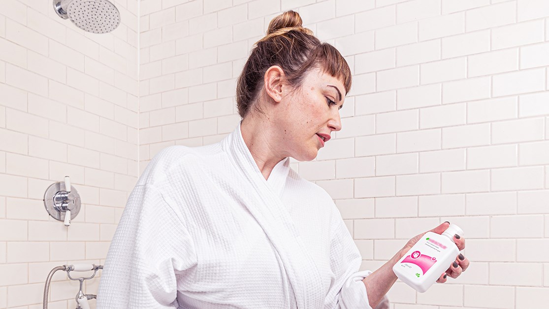 Femme dans la salle de bain avec un Hibiscrub à la main