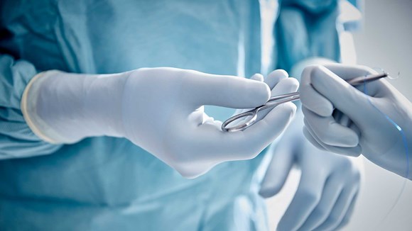 Chirurgen met operatiehandschoenen die een instrument vasthouden